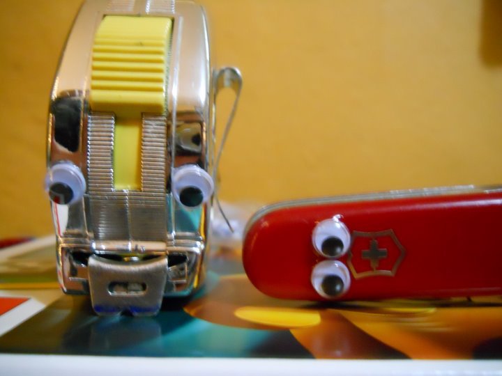A tape measure and Swiss Army Knife with googly eyes attached.